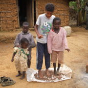 American child with village children shelling groundnuts with their feet