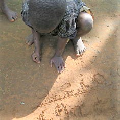 child writing in the dirt