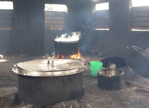 kitchen with black walls, pots cooking over firewood, lots of smoke