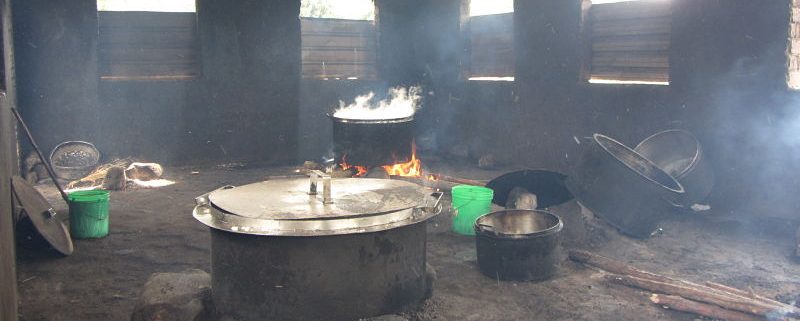 kitchen with black walls, pots cooking over firewood, lots of smoke