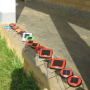 row of a dozen small solar lanterns charging on a sunny porch