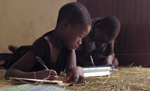 Tanzanian children doing homework on the floor