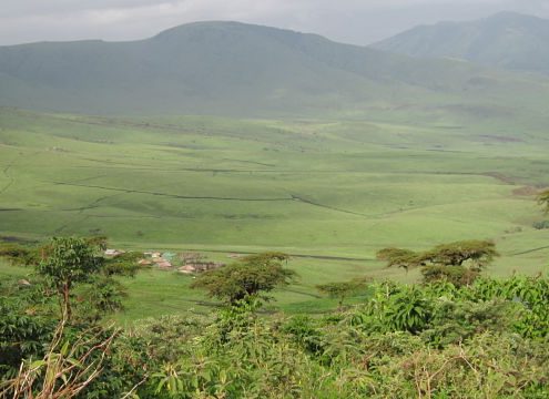 rolling green hills with cluster of village huts