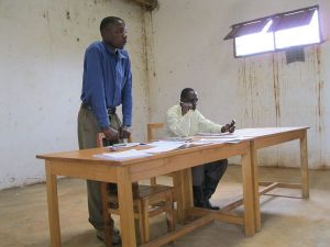 two Tanzanian men at a table covered with papers