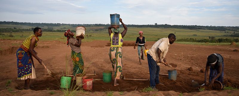 village women moving dirt on soccer field