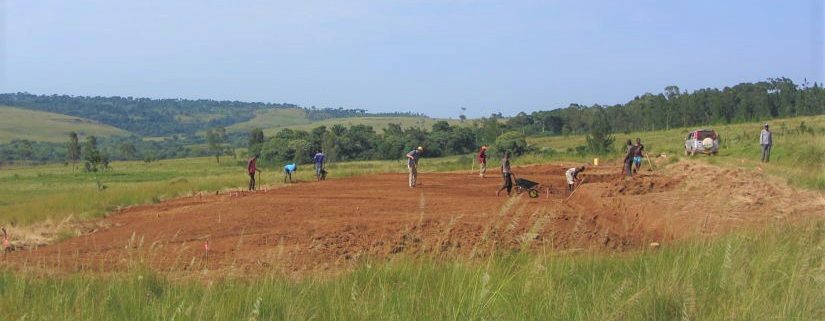 men working in red dirt with shovels, hoes and wheelbarrows