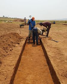 workers measuring a partially-dug foundation trench