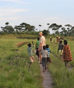 Caucasian man with Tanzanian village kids following him on a rural path