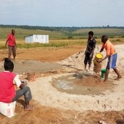 men dumping sand into depression in the soil