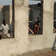Man looking out window of partially constructed school building