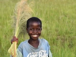 girl smiling and waving a bunch of long grass