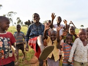 group of children smiling and waving hands