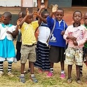 group of young Tanzanian children smiling and waving