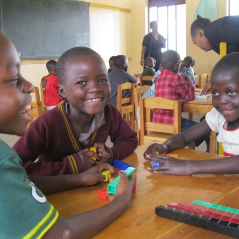 smiling kids in a classroom working with unifix cubes