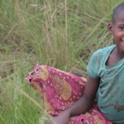 girl in torn clothes with big smile sitting on a rock