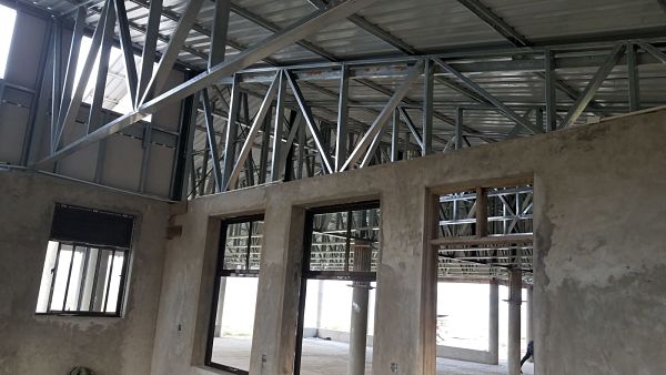 inside room with lots of steel trusses and underside of steel roof visible