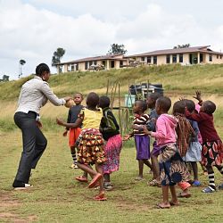 teacher outside playing ball with students 