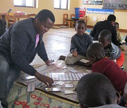 man sitting on mat helping children teacher on another mat in background