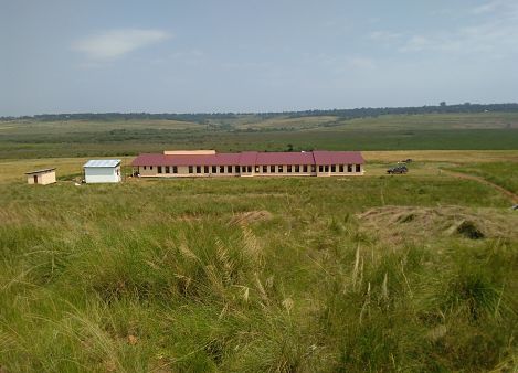 long school building surrounded by grass fields