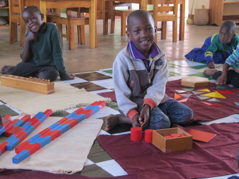 Children on floor mats working with brightly colored wooden Montessori materials