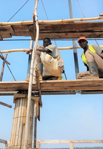workers on bamboo and wood scaffolding with only blue sky in background