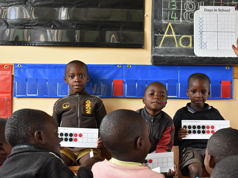 Children displaying cards with red and black dots in rectangular frames of twenty