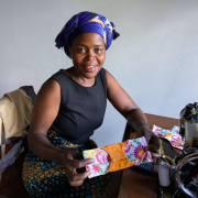 Woman at sewing machine holding colorful cloth pad