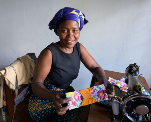 Woman at sewing machine holding colorful cloth pad