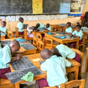 students working at tables and on the floor with 2 teachers in the classroom