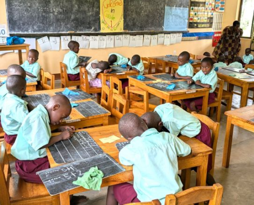 students working at tables and on the floor with 2 teachers in the classroom