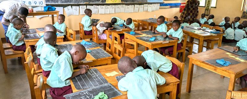 students working at tables and on the floor with 2 teachers in the classroom
