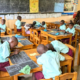 students working at tables and on the floor with 2 teachers in the classroom
