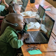 young children at laptops wearing headphones